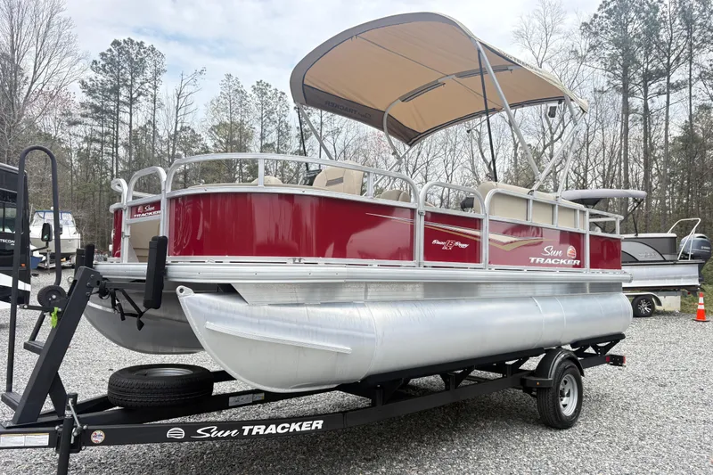 The Image of 2025 Sun Tracker Bass Buggy 18 DLX pontoon boat on trailer, parked outdoors. - 1