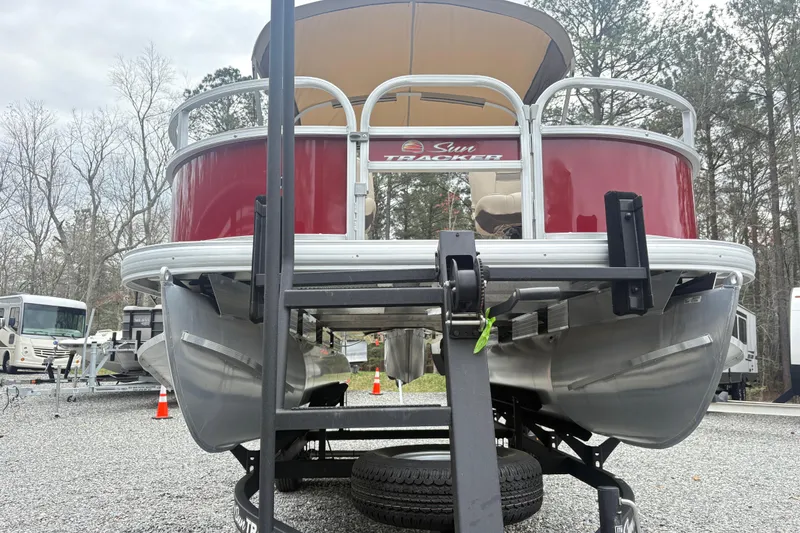 Slide: The Image of 2025 Sun Tracker Bass Buggy 18 DLX pontoon boat on trailer, parked outdoors. - 5