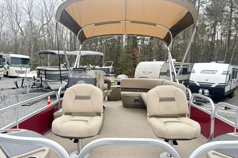 Slide: The Image of 2025 Sun Tracker Bass Buggy 18 DLX pontoon boat with beige seating and canopy in a lot. - 6