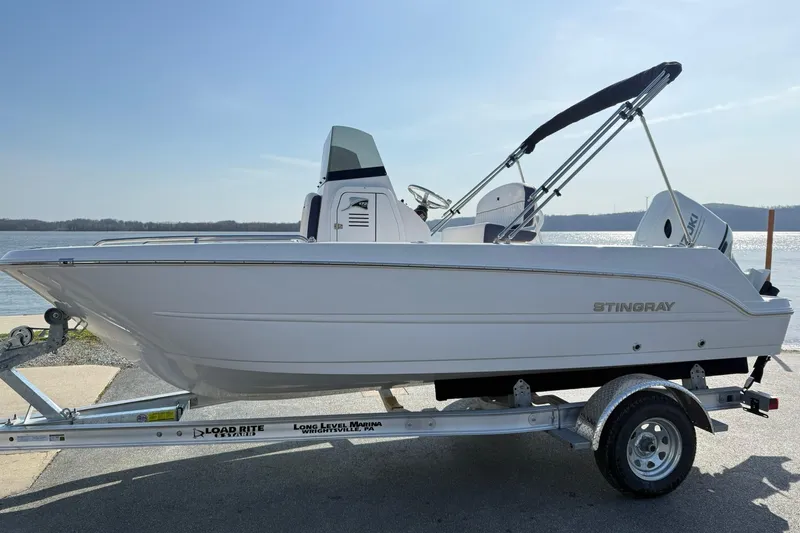 The Image of 2026 Stingray 173 CC boat on trailer by waterfront, clear sky background. - 1