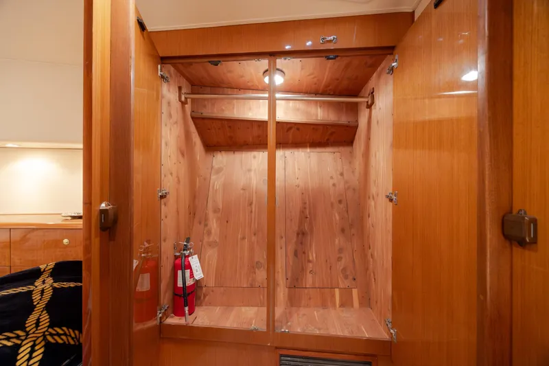 Slide: The Image of Wooden closet interior on a 2000 Viking 55 Convertible yacht, featuring fire extinguishers. - 52
