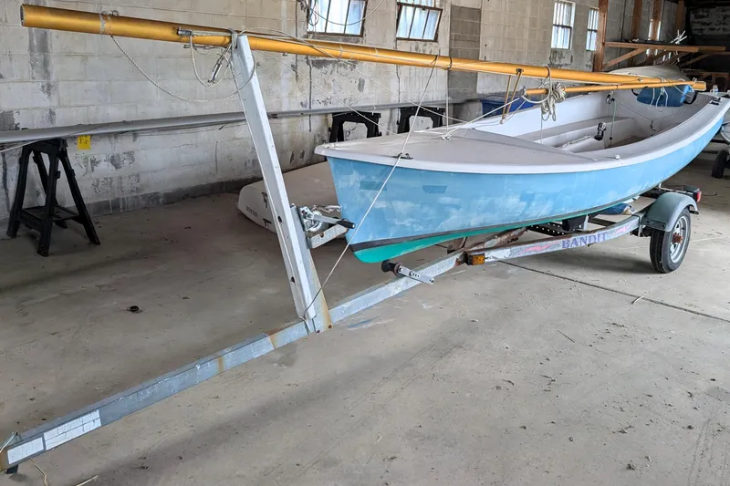 The Image of 1972 Oday Widgeon sailboat on trailer in a garage setting. - 1