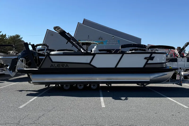 The Image of Alera M23Q 2026 pontoon boat displayed in a parking lot under clear blue skies. - 1