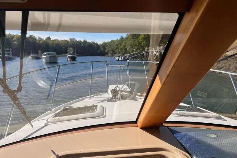 Slide: The Image of 2014 Cutwater C-26 boat navigating a serene river with surrounding trees and moored boats. - 12