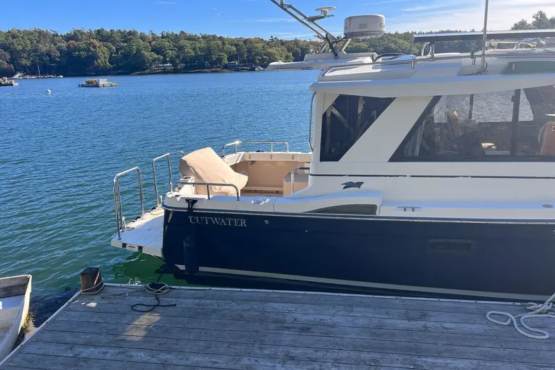 Slide: The Image of 2014 Cutwater C-26 boat docked on a serene lake with lush green surroundings. - 3