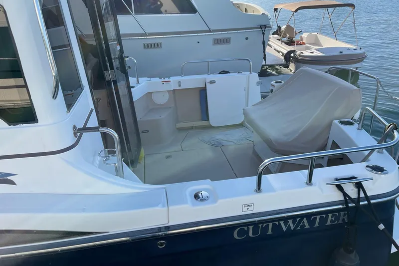 Slide: The Image of 2014 Cutwater C-26 boat docked, featuring spacious deck and covered seating area. - 4