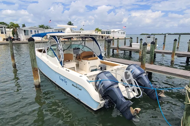 The Image of 2010 World Cat 290 DC boat docked, featuring dual Yamaha engines, under a partly cloudy sky. - 0