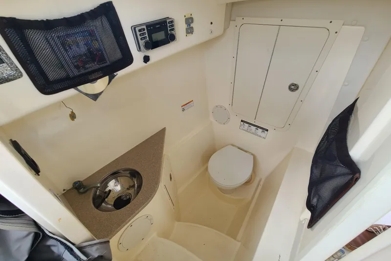 Slide: The Image of Interior of 2010 World Cat 290 DC boat featuring a compact bathroom with sink and toilet. - 14