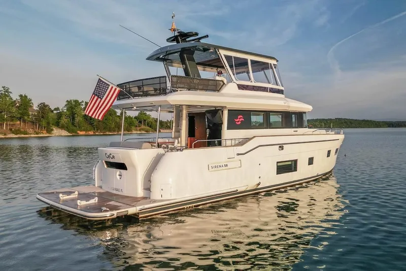 Slide: The Image of Luxury 2021 Sirena 58 yacht on serene lake, featuring sleek design and American flag. - 1