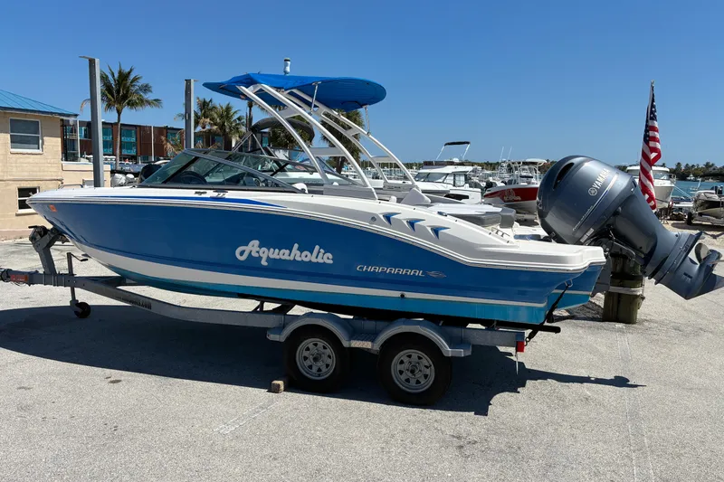 Slide: The Image of 2019 Chaparral 21 H2O Sport boat on trailer, blue and white design, dockside setting. - 5