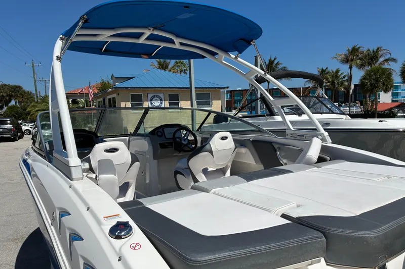 Slide: The Image of 2019 Chaparral 21 H2O Sport boat with blue canopy, parked outdoors. - 6