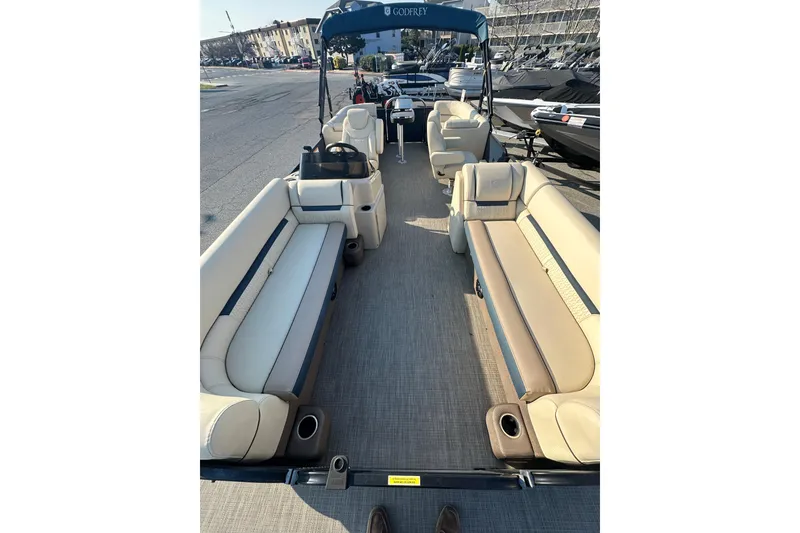 Slide: The Image of 2022 Sweetwater 2386 SB pontoon boat interior with beige seating and steering console. - 7