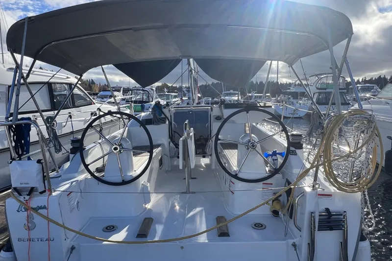 Slide: The Image of 2024 Beneteau Oceanis 30.1 sailboat with dual steering wheels in a marina. - 2