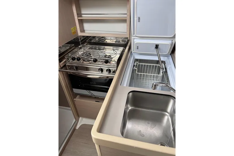 Slide: The Image of Modern kitchen area in 2024 Beneteau Oceanis 30.1 yacht, featuring stove, sink, and storage. - 22