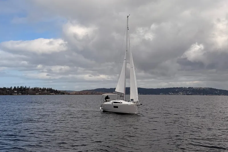Slide: The Image of 2024 Beneteau Oceanis 30.1 sailing on a cloudy day, surrounded by scenic landscape. - 33