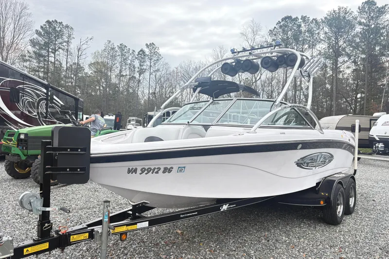 The Image of 2005 Correct Craft Nautique boat on trailer, parked outdoors with trees in background. - 1