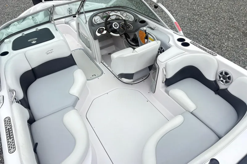 Slide: The Image of 2005 Correct Craft Nautique boat interior with white and gray seating, steering console, and cup holders. - 8