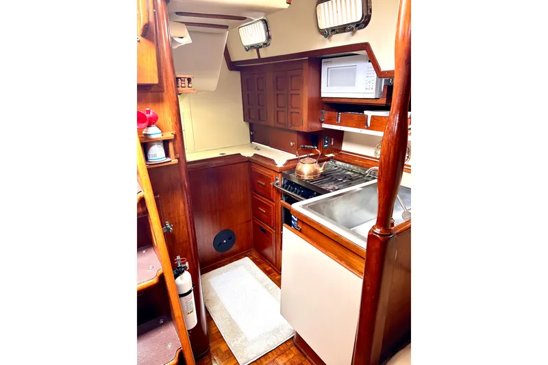Slide: The Image of 1984 Endeavour 40 CC yacht kitchen with wooden cabinetry, stove, sink, and microwave. - 17