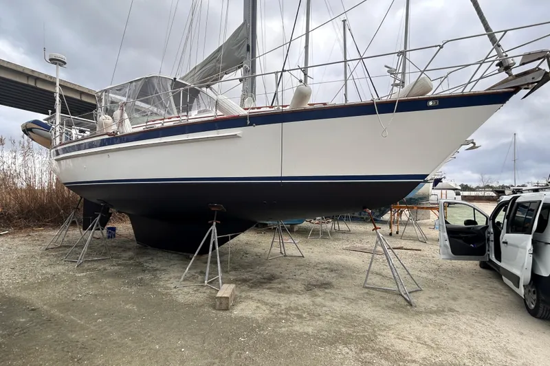 Slide: The Image of 1984 Endeavour 40 CC sailboat on stands, under cloudy sky, near a vehicle. - 6