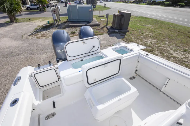 Slide: The Image of 2014 Sea Hunt Gamefish 25 boat with open storage compartments and dual outboard motors. - 14