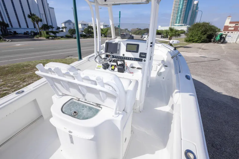 Slide: The Image of 2014 Sea Hunt Gamefish 25 boat interior with console and seating, parked near buildings. - 15