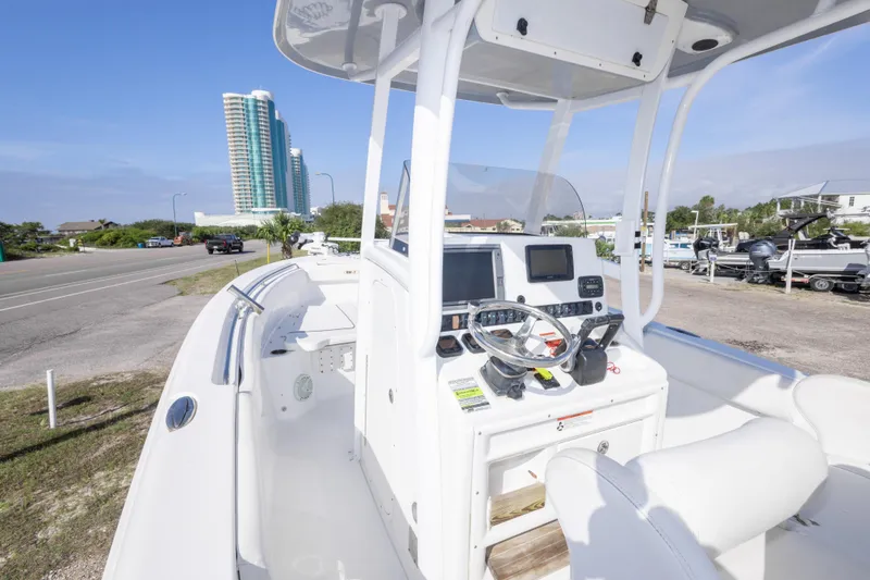 Slide: The Image of 2014 Sea Hunt Gamefish 25 boat with modern console, parked near a coastal road. - 17