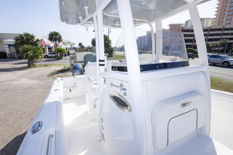 Slide: The Image of 2014 Sea Hunt Gamefish 25 boat with center console, parked near a coastal road. - 30