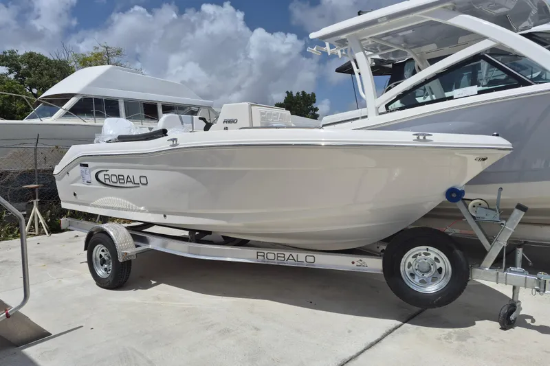 The Image of 2026 Robalo R180 Center Console boat on trailer, parked outdoors. - 0