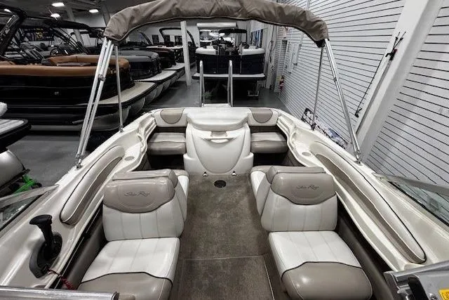 Slide: The Image of 2002 Sea Ray 182 Bow Rider interior with beige seating and canopy in showroom. - 12
