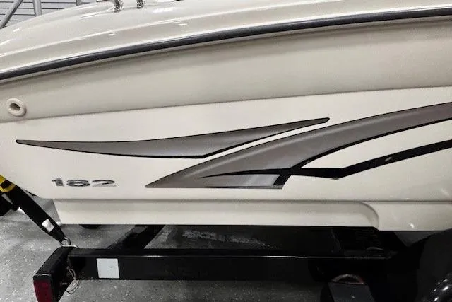 Slide: The Image of 2002 Sea Ray 182 Bow Rider boat side view with sleek graphics and trailer. - 20