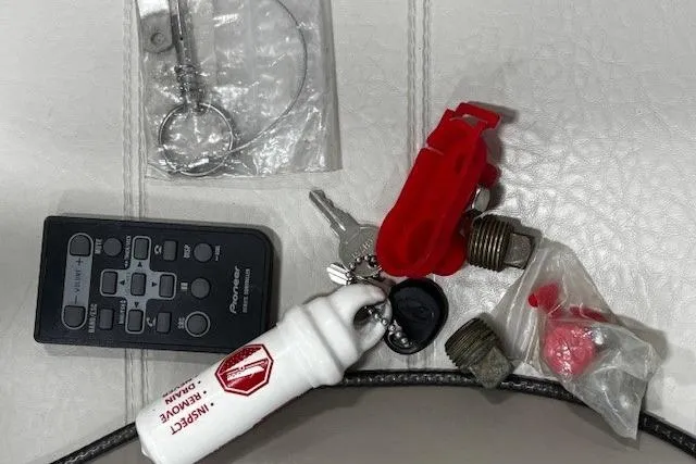 Slide: The Image of Assorted boating accessories on white surface, including keys, remote, and safety gear for 2002 Sea Ray 182 Bow Rider. - 25