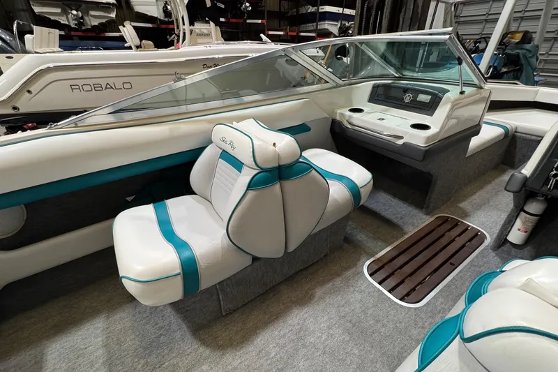 Slide: The Image of 1991 Sea Ray 185 Bow Rider interior with teal and white seating, dashboard, and carpeted flooring. - 4