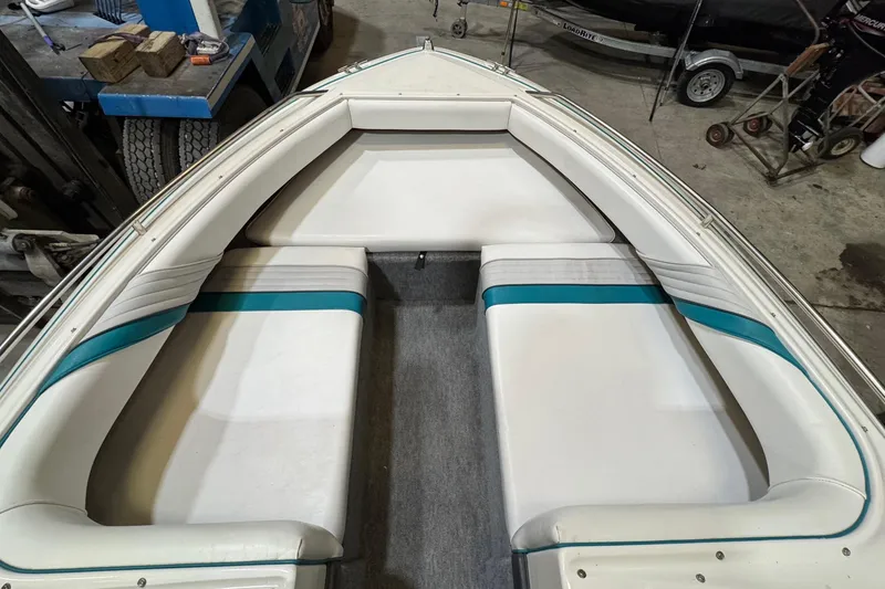 Slide: The Image of 1991 Sea Ray 185 Bow Rider interior with white and teal seating in a garage setting. - 8