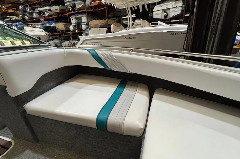 Slide: The Image of 1991 Sea Ray 185 Bow Rider interior with white and teal seating in a storage facility. - 9