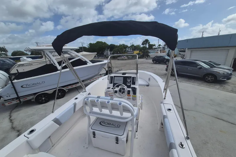 Slide: The Image of 2026 Robalo R180 Center Console boat with canopy, parked outdoors under cloudy sky. - 15