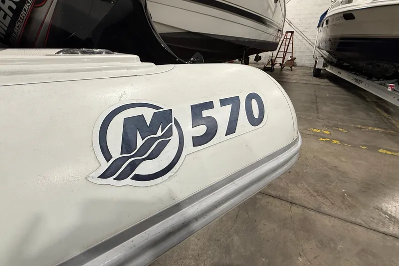 Slide: The Image of White Mercury 570 boat in a warehouse, showcasing logo and model number. - 2