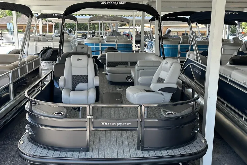 Slide: The Image of 2026 Ranger Reata 223FC pontoon boat with luxurious seating in a showroom. - 2