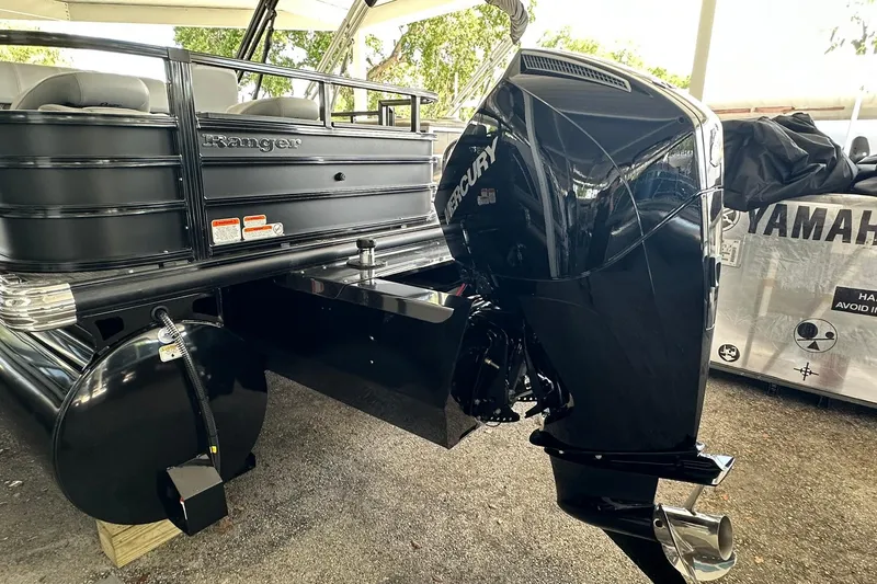 Slide: The Image of 2026 Ranger Reata 223FC pontoon boat with Mercury outboard motor, parked under a canopy. - 38