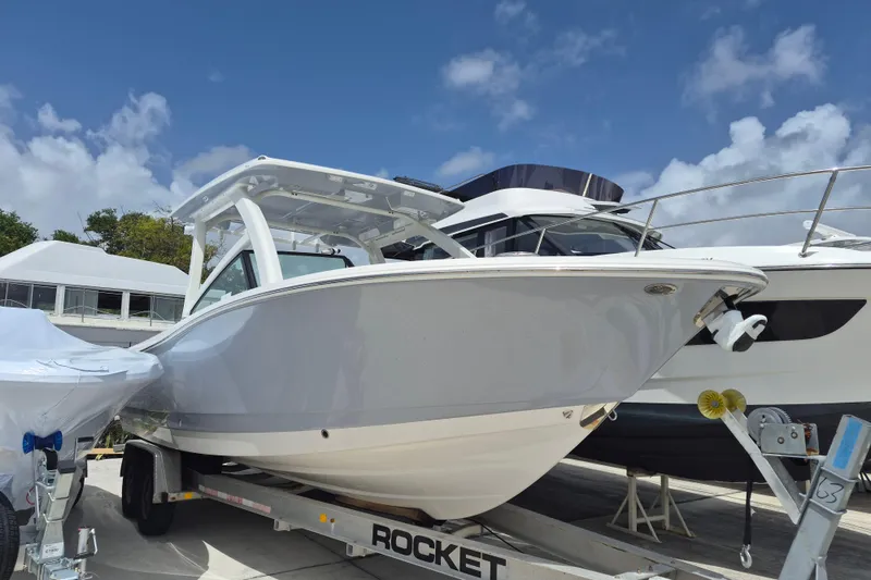 The Image of 2026 Robalo R277 Dual Console boat on trailer under clear blue sky. - 1