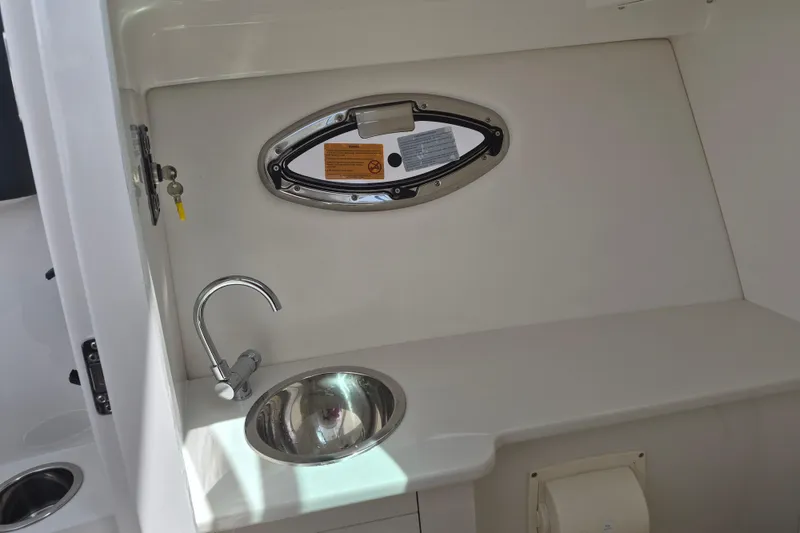 Slide: The Image of 2026 Robalo R277 Dual Console boat interior with sink and porthole window. - 11