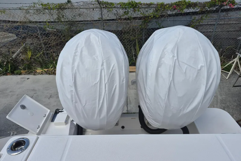 Slide: The Image of 2026 Robalo R277 Dual Console with covered outboard engines, docked near a fence. - 17