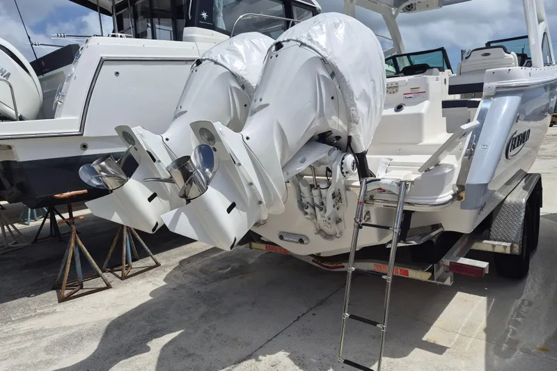 Slide: The Image of 2026 Robalo R277 Dual Console boat with twin outboard engines on a trailer. - 18