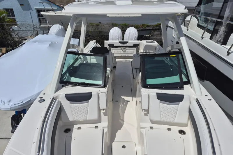 Slide: The Image of 2026 Robalo R277 Dual Console boat interior with seating and windshield, docked outdoors. - 2