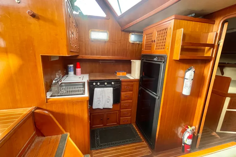 Slide: The Image of 1986 Tung Hwa aft cabin kitchen with wooden cabinetry, stove, and refrigerator. - 23