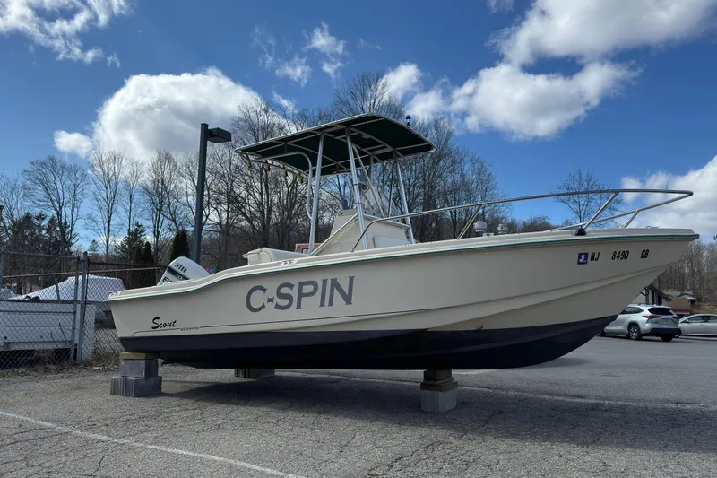 The Image of 1996 Scout 202 Dorado boat named "C-SPIN" on blocks under a cloudy sky. - 1