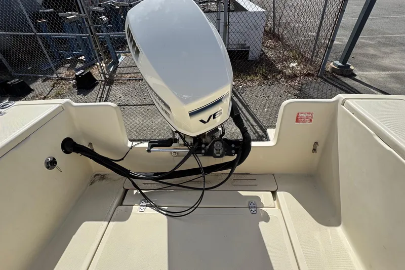 Slide: The Image of 1996 Scout 202 Dorado boat with V6 outboard motor, parked near a chain-link fence. - 10