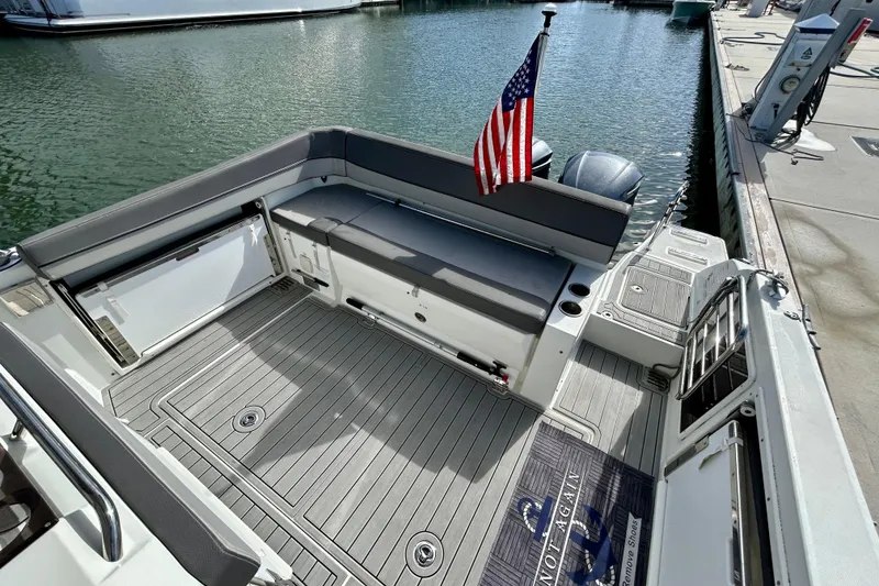 Slide: The Image of 2019 Jeanneau Leader 9.0 WA boat deck with seating, American flag, and waterfront view. - 15