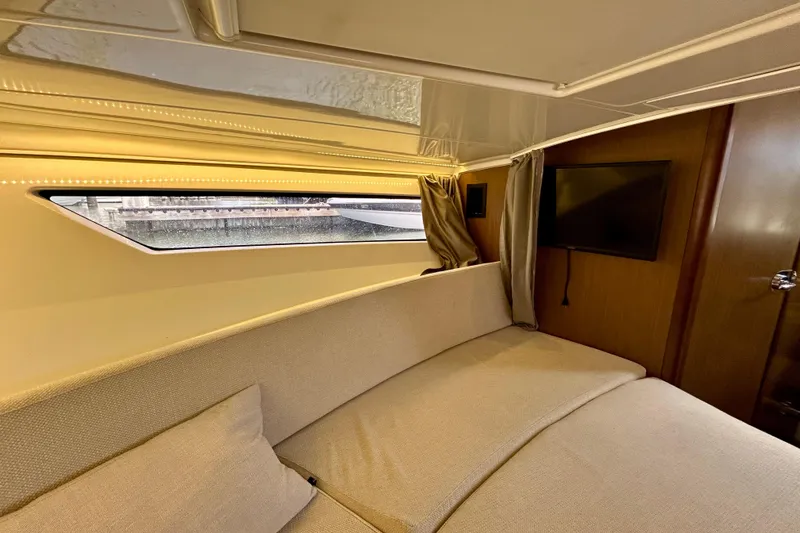 Slide: The Image of Interior of 2019 Jeanneau Leader 9.0 WA boat, featuring cozy seating and a window view. - 24