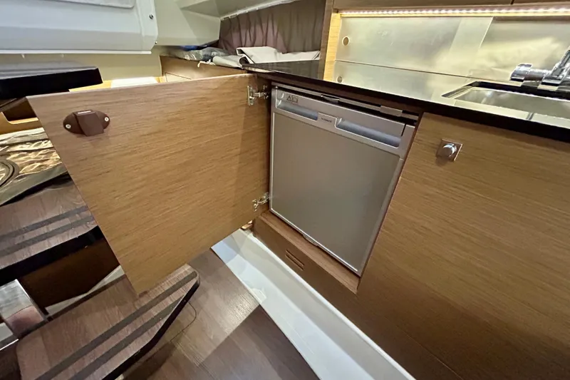 Slide: The Image of 2019 Jeanneau Leader 9.0 WA interior with open cabinet and compact fridge. - 27