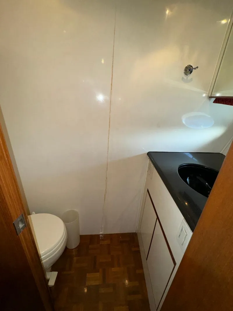Slide: The Image of 2004 Ocean Alexander 42 yacht bathroom with toilet, sink, and wooden flooring. - 24